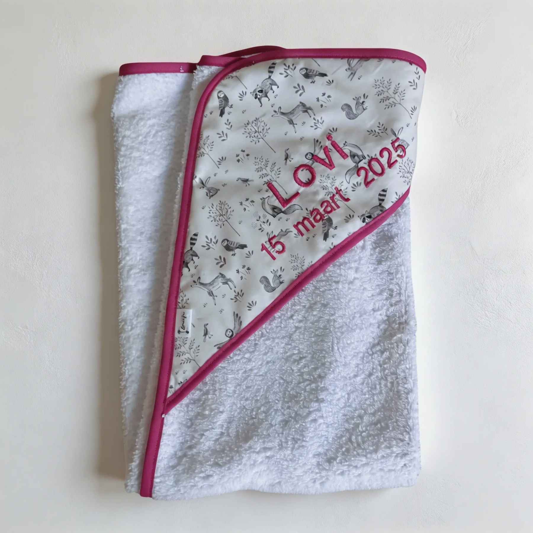 Handgemaakte badcape met naam en geboortedatum van Leonietje's in neutraal bosdieren stof met roze geborduurde letters