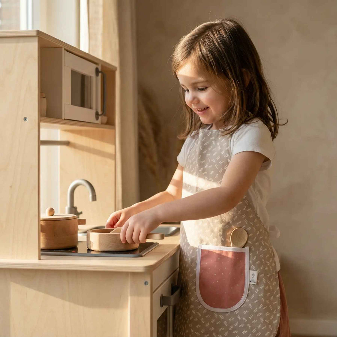 Handgemaakt groen kinderschortje met bladerenprint en blush glitter dots zakje inclusief houten pollepel van Leonietje’s