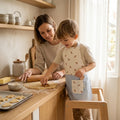 Handgemaakt kinderschortje met croissantprint en lichtblauw hartjes onderstuk van Leonietje's – 100% OEKO-TEX katoen voor kinderen van 2 tot 5 jaar. Jongen samen met moeder koekjes bakken. 
