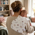 Handgemaakte spuugdoek over de schouder met dennenappelprint in oudroze en roestbruine tinten, 100% katoen voorzijde en badstof achterkant, ergonomische vorm met inham voor de nek — Leonietje's
moeder met baby over de schouder tijdens een boertje laten
