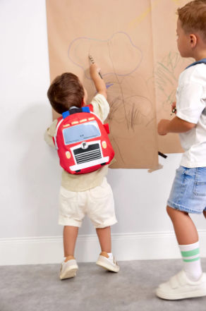 Peuter met Lässig Tiny Backpack Brandweerwagen rugzak tijdens het spelen buiten